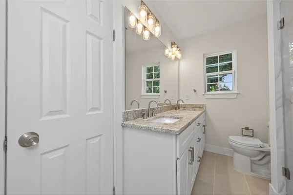 a bathroom with a granite countertop sink a toilet and a mirror