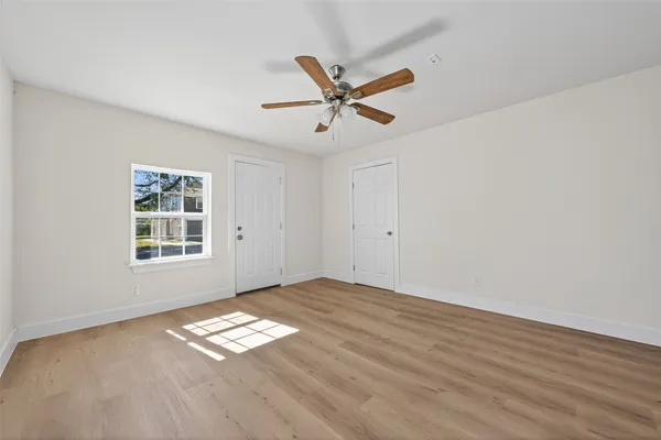 a view of empty room with wooden floor and window