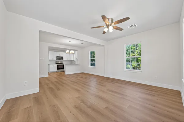 a view of an empty room with window and wooden floor