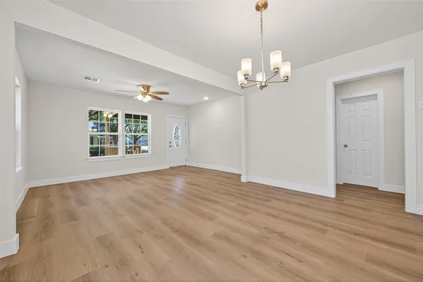 a view of an empty room with a window and wooden floor