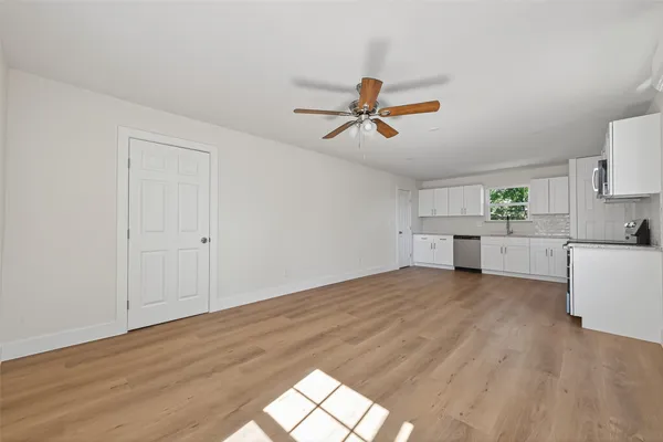 a view of empty room with wooden floor and ceiling fan