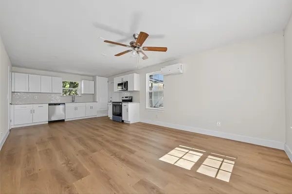 a view of empty room with wooden floor and ceiling fan