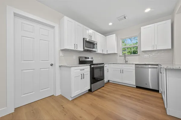 a kitchen with white cabinets stainless steel appliances and window