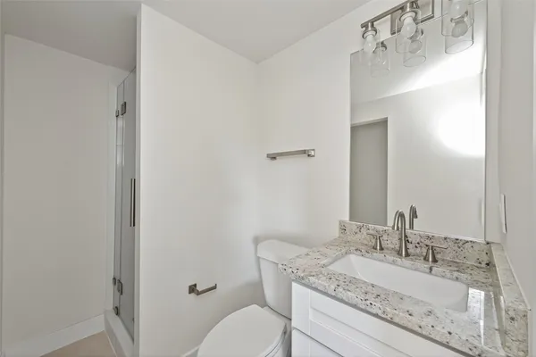 a bathroom with a granite countertop sink mirror vanity and toilet