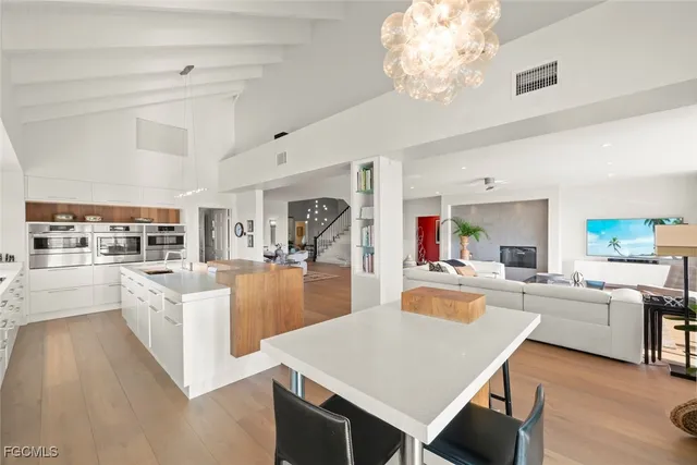 a large white kitchen with lots of counter space dining table and stainless steel appliances