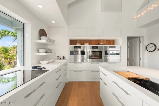 a large white kitchen with kitchen island and stainless steel appliances