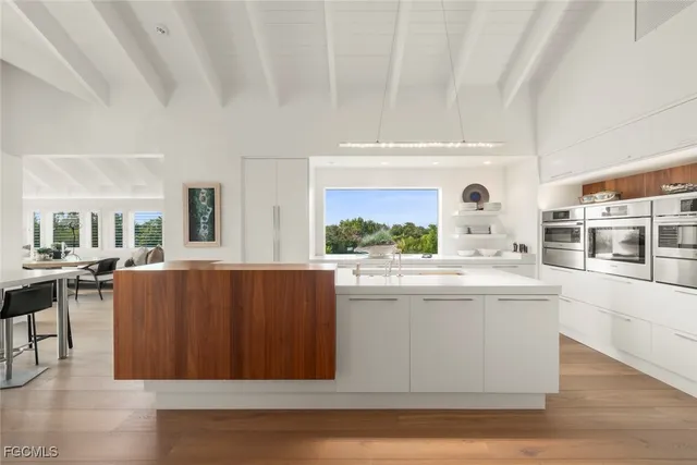 a view of kitchen with kitchen island stainless steel appliances wooden floor and living room view