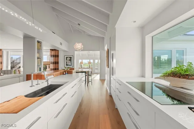 a large white kitchen with kitchen island a large counter top space a large window and stainless steel appliances