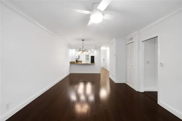 an empty room with wooden floor chandelier fan and windows