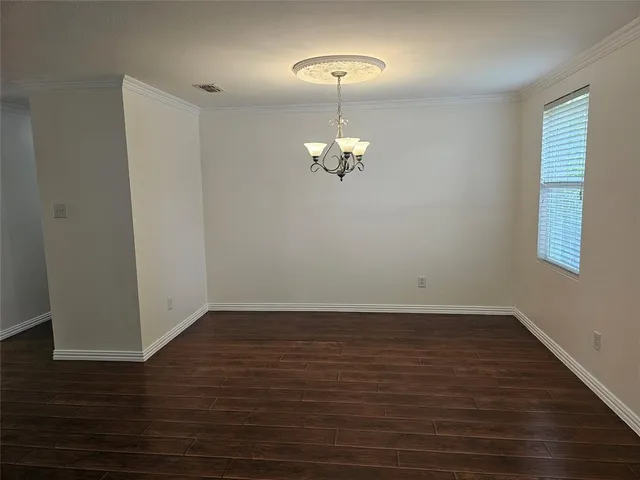 a view of an empty room with wooden floor and a chandelier