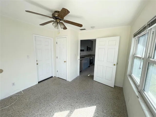 a view of an empty room and a kitchen with a sink