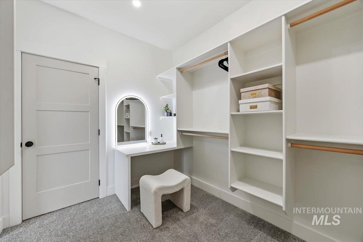 2005 Sparrow Street Rupert, ID 83350 - Photo 21 of 30 Built-in custom closet system featuring white shelving, wood hanging rods, and a dedicated vanity with an arched, illuminated mirror
