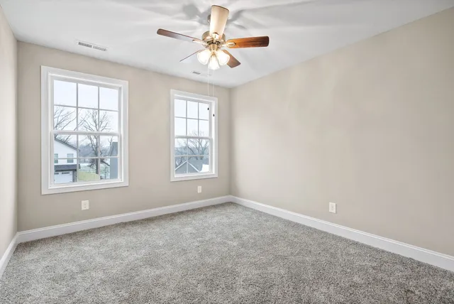an empty room with windows and chandelier fan