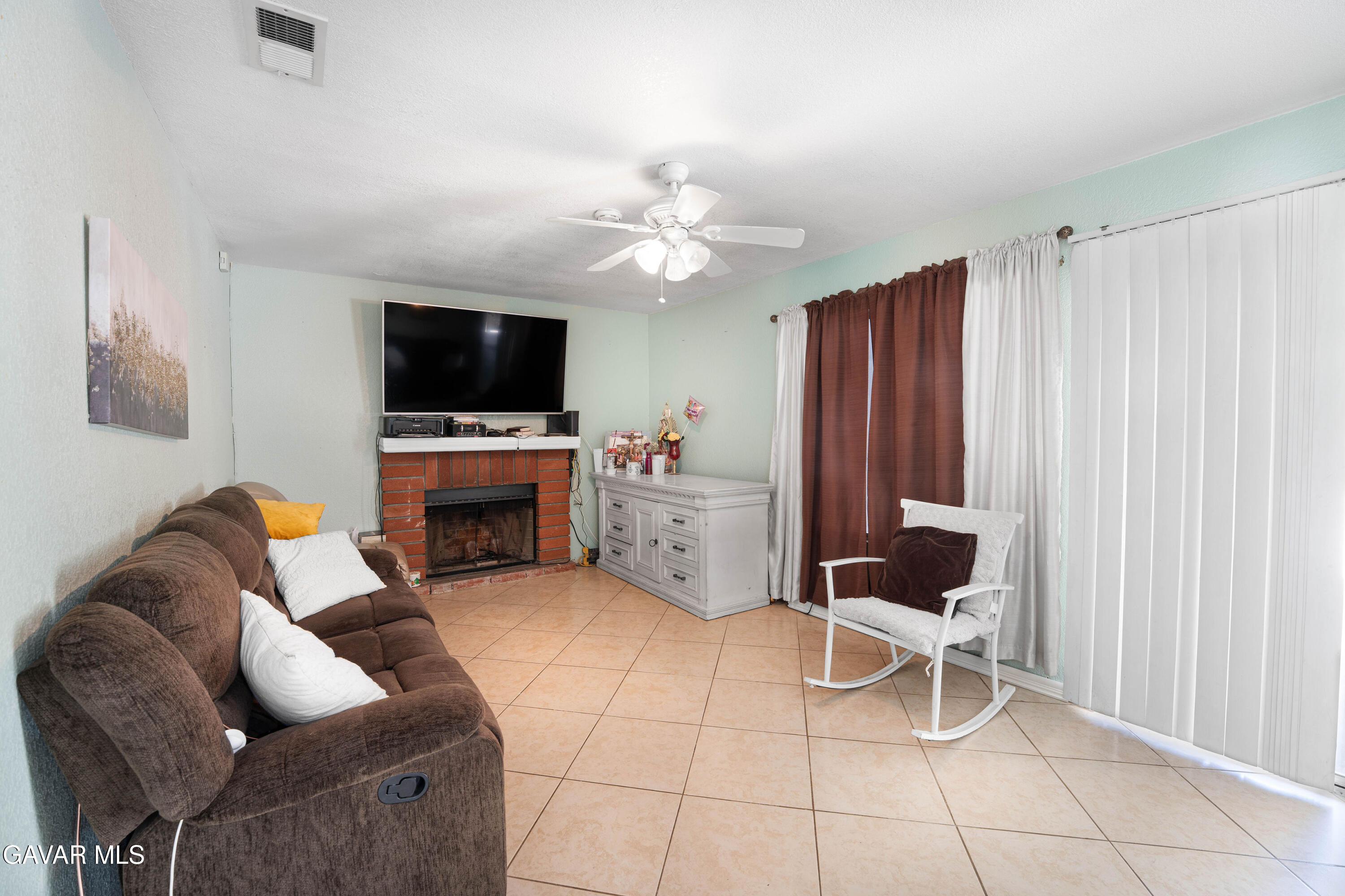 5009 East Ave R 11 Palmdale, CA 93552 - Photo 12 of 23 a living room with furniture a fireplace and a flat screen tv