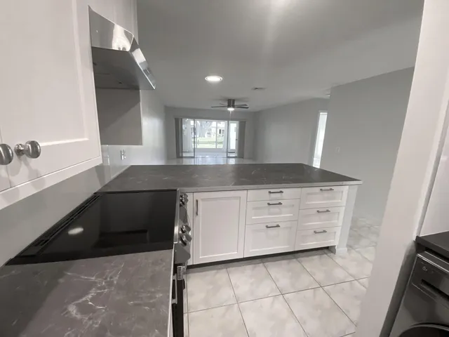 a kitchen with granite countertop white cabinets and window