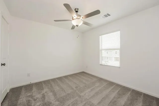 an empty room with a ceiling fan and window