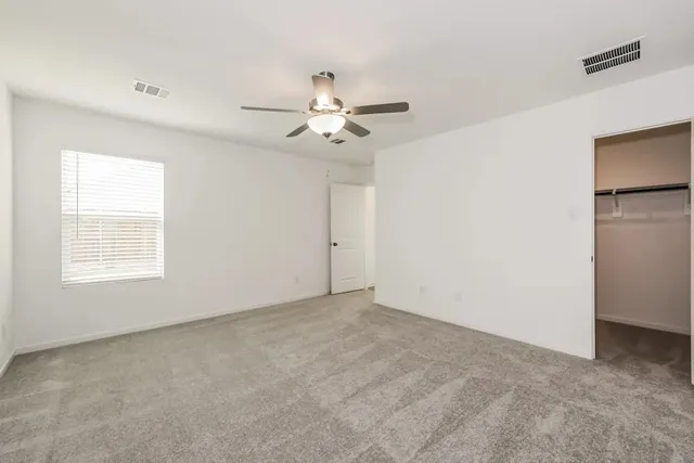 an empty room with ceiling fan and window