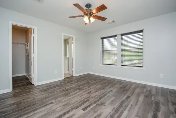 a view of an empty room with window and wooden floor