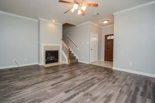a view of an empty room with wooden floor fireplace and a window