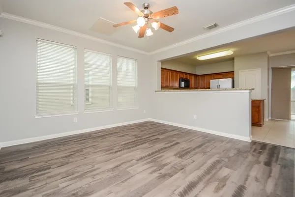 a view of empty room with wooden floor and fan