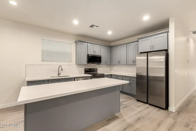 a large kitchen with stainless steel appliances kitchen island a large counter top a sink and a stove