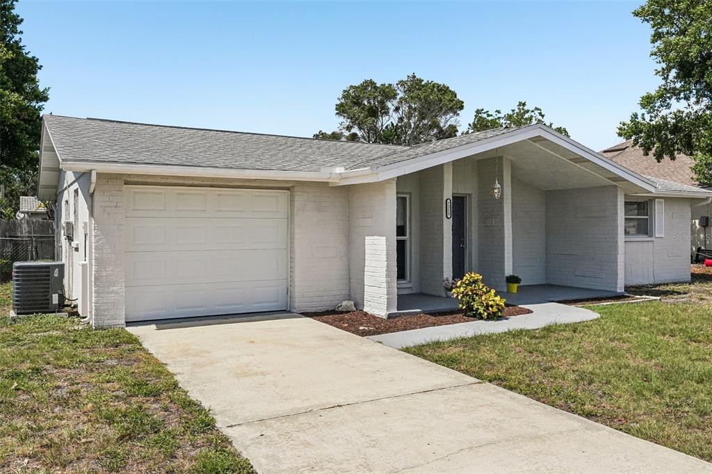 7215 Mayfield Drive Port Richey, FL 34668 - Photo 2 of 52 a front view of a house with a yard and garage