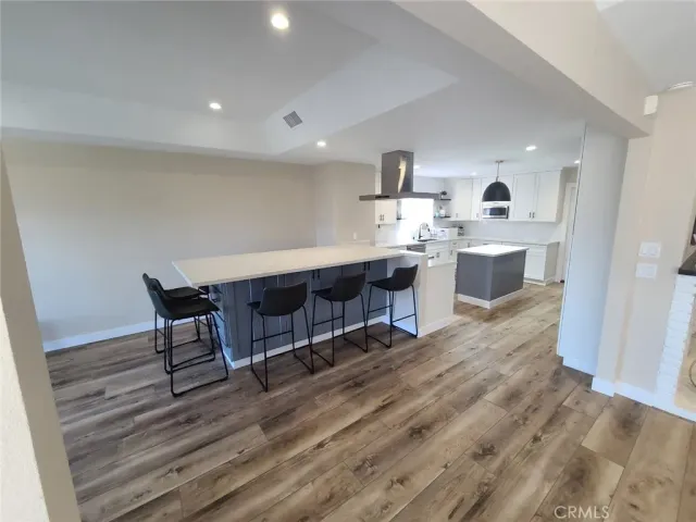 a living room with stainless steel appliances kitchen island hardwood floor sink and view living room