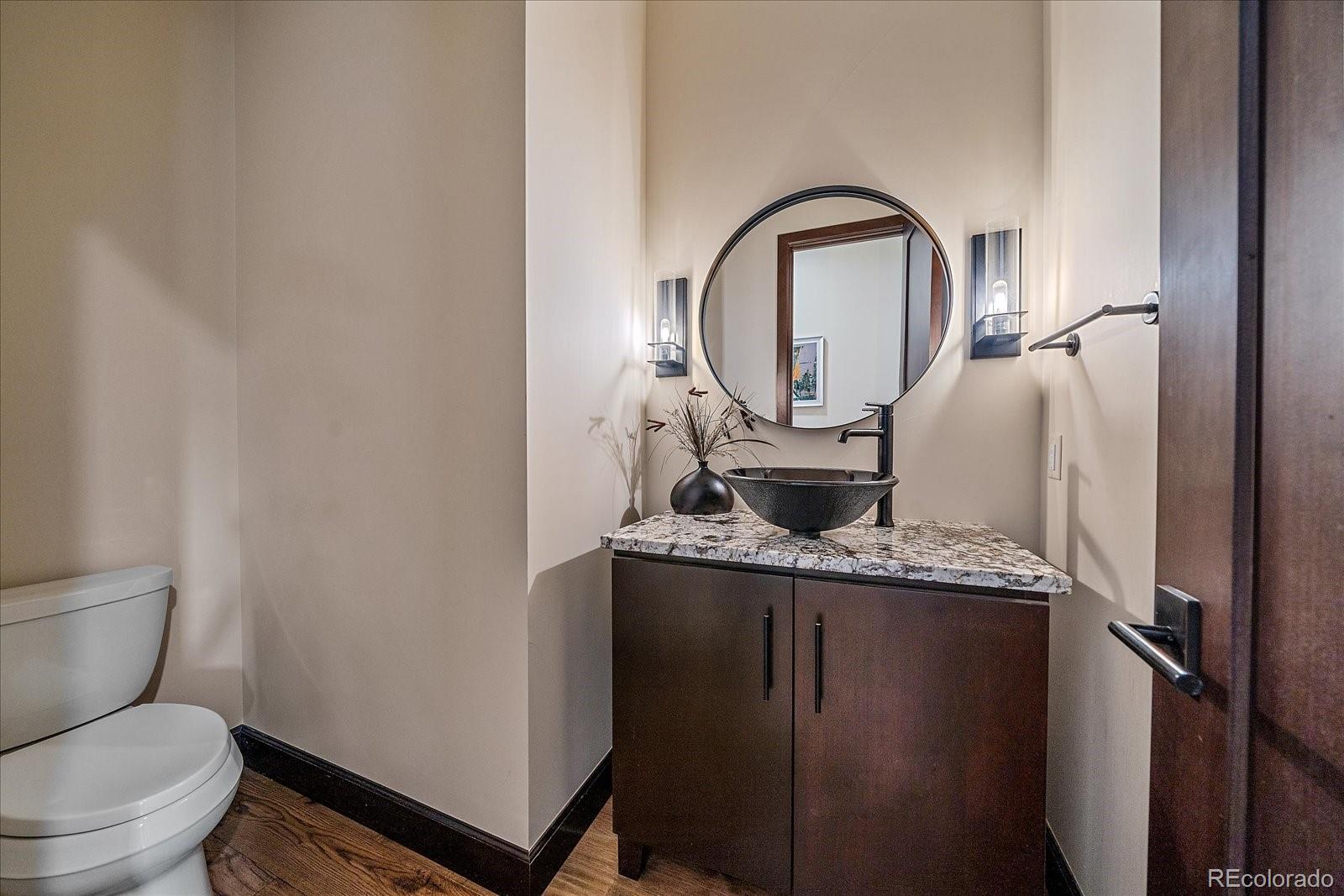 4331 Hilltop Road Evergreen, CO 80439 - Photo 22 of 45 a bathroom with a granite countertop toilet a sink and a mirror