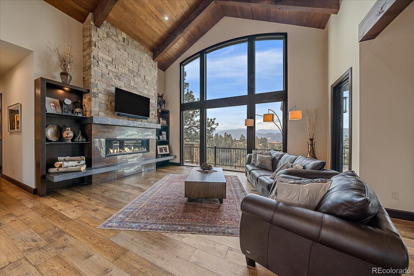 4331 Hilltop Road Evergreen, CO 80439 - Photo 8 of 45 a living room with furniture a flat screen tv and a fireplace