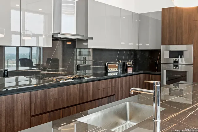 a kitchen with kitchen island granite countertop a refrigerator a sink and wooden cabinets