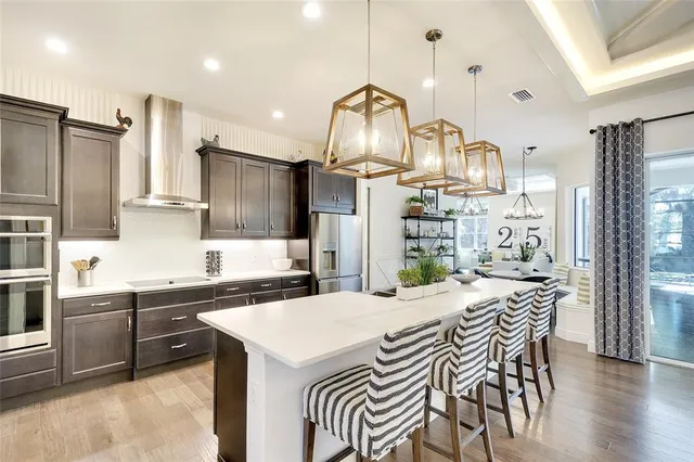 a kitchen with stainless steel appliances kitchen island granite countertop a sink a stove and a refrigerator