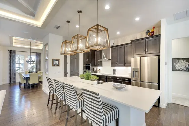 a kitchen with stainless steel appliances a dining table chairs and wooden floor