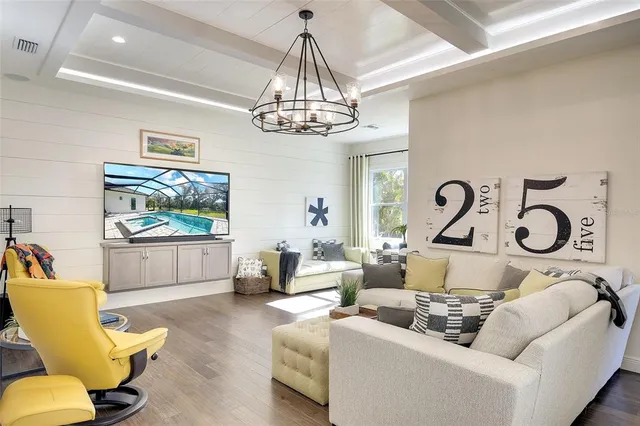 a living room with furniture a chandelier and a flat screen tv