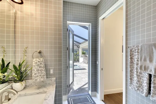 a bathroom with a granite countertop a sink a mirror and shower