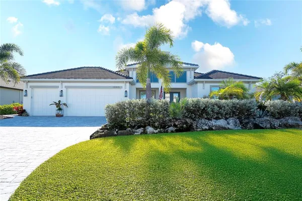 a palm tree sitting in front of a house with a garden