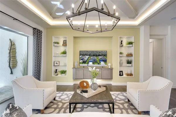 a living room with furniture a chandelier and a dining table with wooden floor