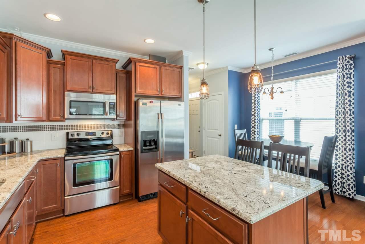2427 Memory Ridge Drive Raleigh, NC 27606 - Photo 8 of 22 a kitchen with stainless steel appliances granite countertop a stove a refrigerator and a wooden cabinets