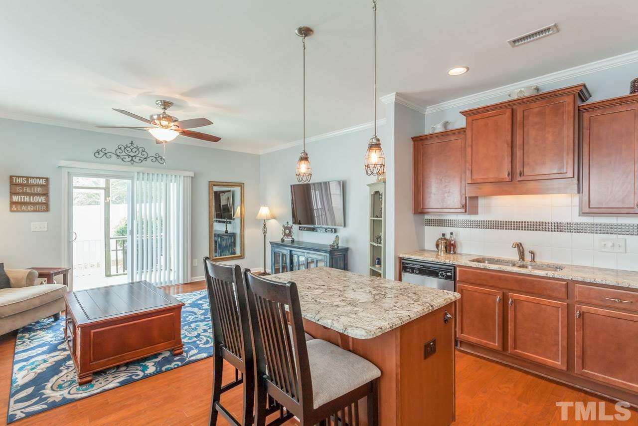 2427 Memory Ridge Drive Raleigh, NC 27606 - Photo 9 of 22 a open kitchen with stainless steel appliances granite countertop a sink a stove a dining table and chairs with wooden floor