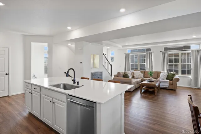 a kitchen with stainless steel appliances granite countertop a refrigerator a stove top oven a sink dishwasher and a refrigerator with wooden floor