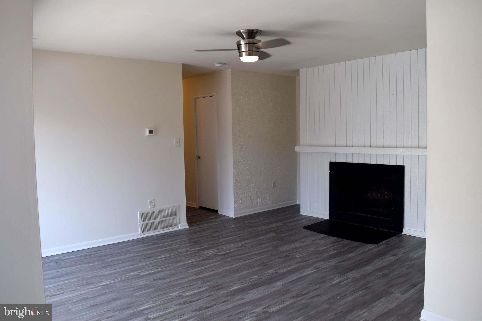 10566 Twin Rivers Road, Unit F1 Columbia, MD 21044 - Photo 11 of 44 an empty room with wooden floor and a fireplace