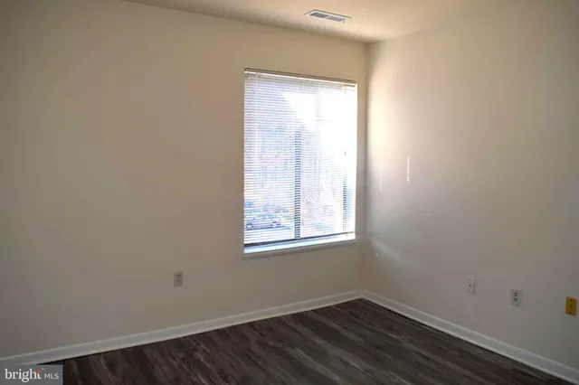 an empty room with wooden floor closet and fan