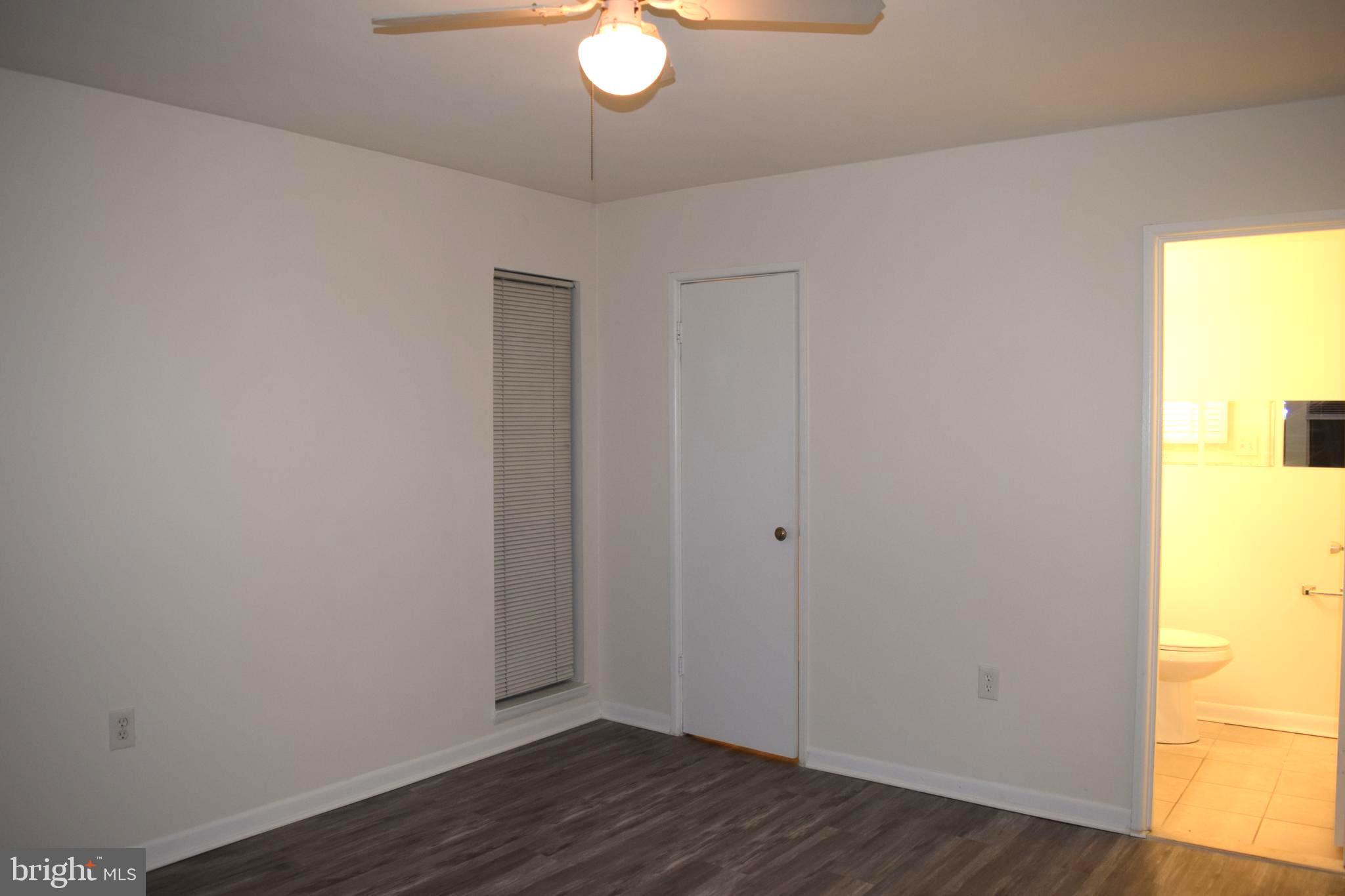 10566 Twin Rivers Road, Unit F1 Columbia, MD 21044 - Photo 21 of 44 a view of an empty room with wooden floor and a window