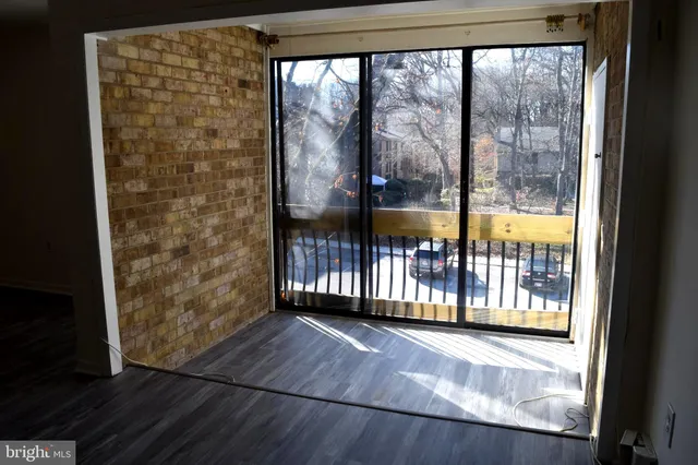 an empty room with wooden floor mirror and fan