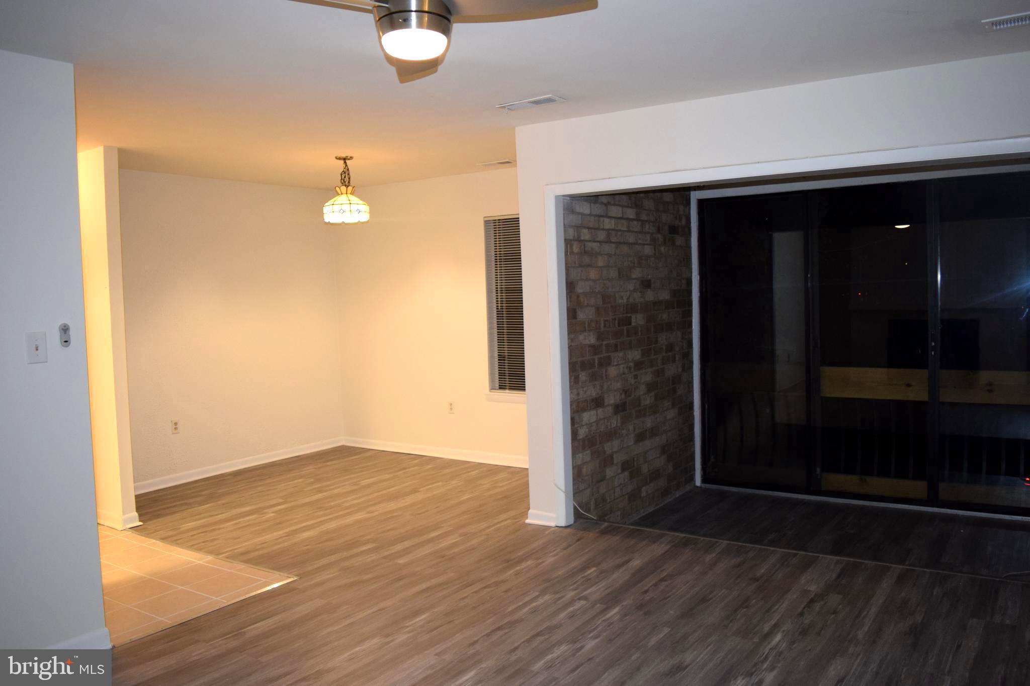 10566 Twin Rivers Road, Unit F1 Columbia, MD 21044 - Photo 9 of 44 an empty room with wooden floor mirror and fan