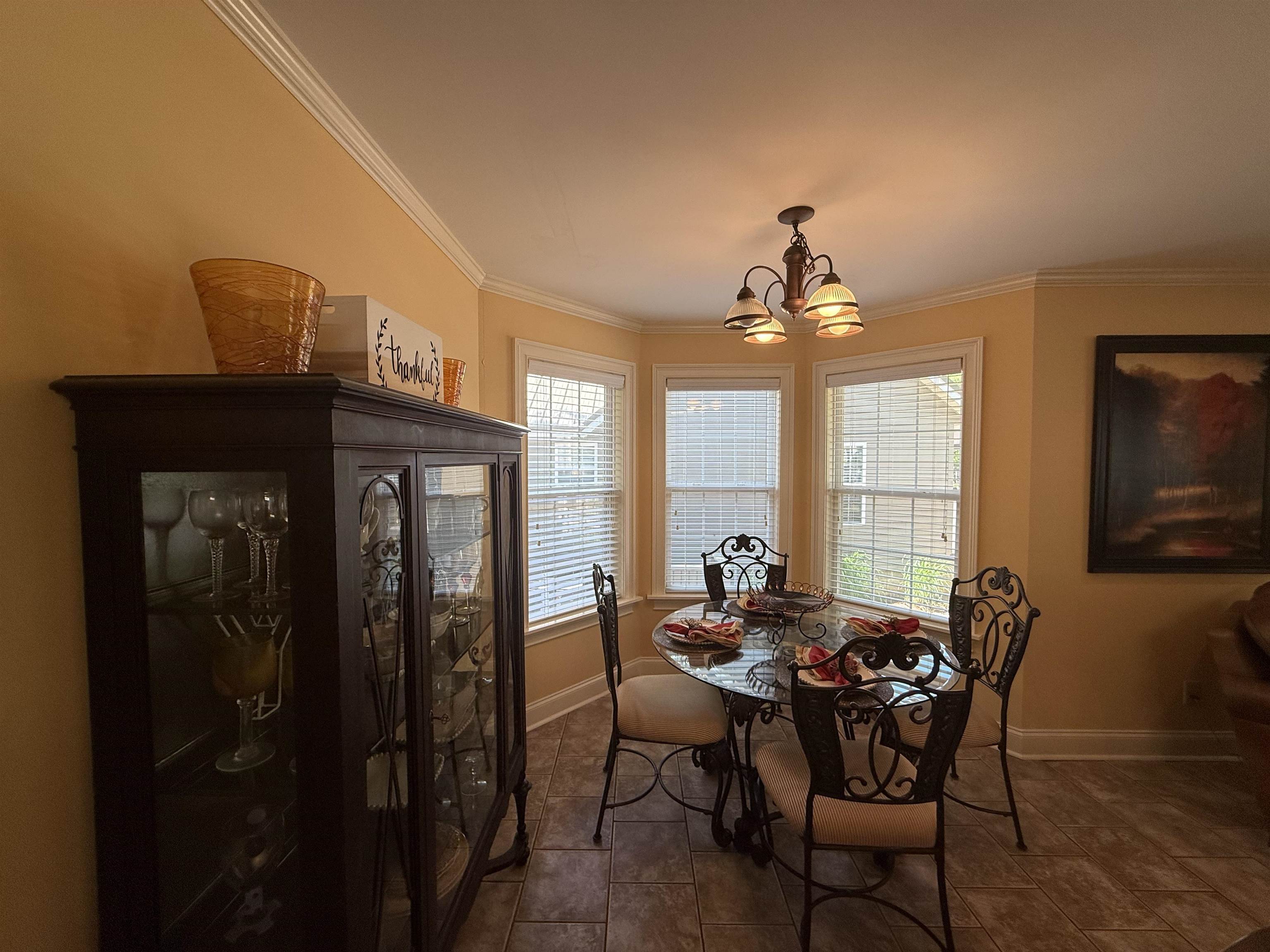 Dining space featuring ornamental molding, dark tile patterned floors, a chandelier, and baseboards