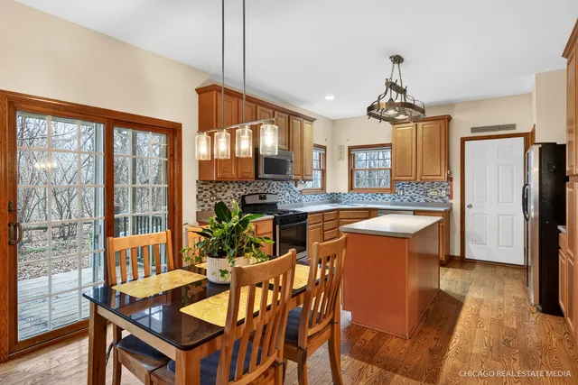 a kitchen with stainless steel appliances granite countertop a stove a refrigerator a sink dishwasher a dining table and chairs with wooden floor