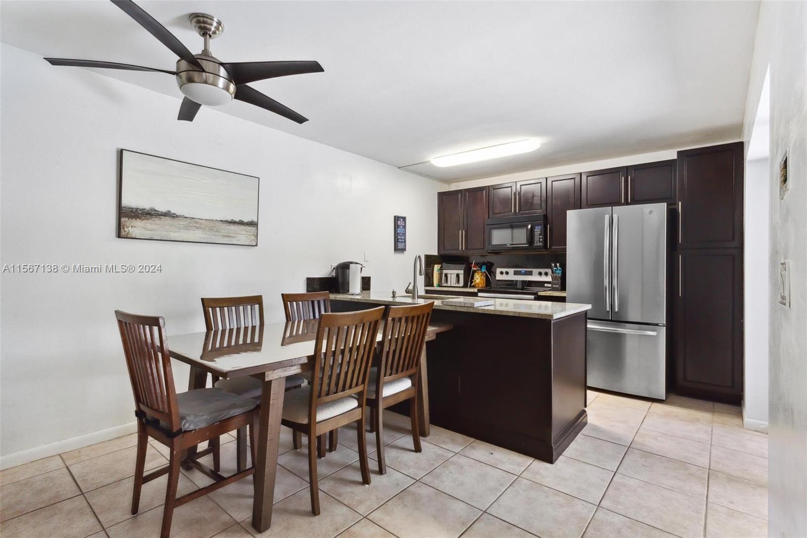 8379 Boca Rio Drive Boca Raton, FL 33433 - Photo 5 of 30 a kitchen with a table chairs refrigerator and microwave