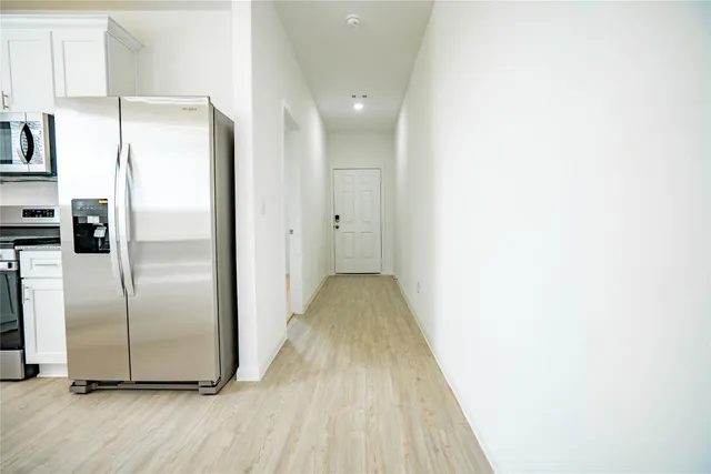 a kitchen with stainless steel appliances granite countertop a stove top oven a sink dishwasher and a refrigerator with wooden floor