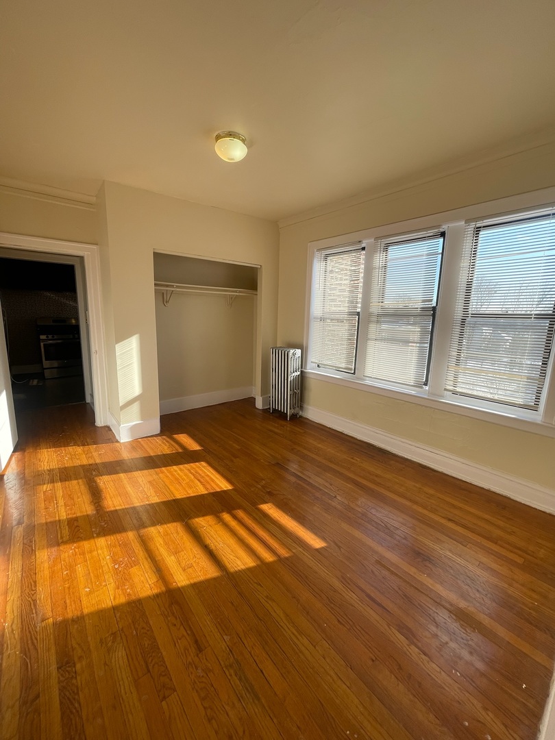 117 East 68th Street, Unit 3 Chicago, IL 60637 - Photo 8 of 17 an empty room with wooden floor and windows