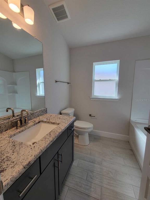 4537 Southwest 91st Ln Road Ocala, FL 34476 - Photo 16 of 18 a bathroom with a granite countertop sink a toilet and mirror